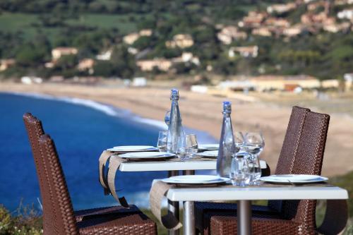 two tables with wine glasses and a view of the beach at Village de vacances Paese di Lava, Grand Ajaccio in Alata