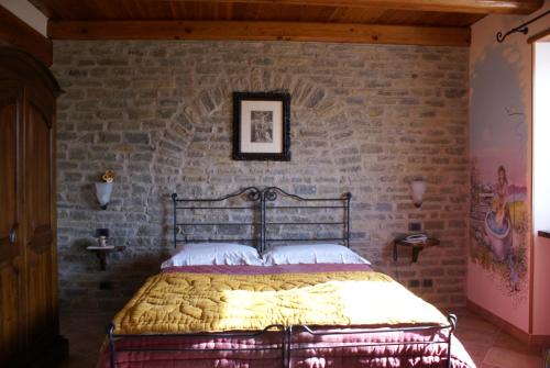 een bed in een kamer met een bakstenen muur bij Agriturismo La Cascina in Bossolasco
