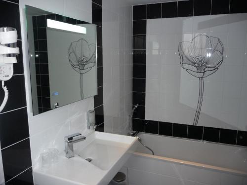 a bathroom with a mirror, sink, and bathtub at Hôtel Spunta Di Mare in Ajaccio