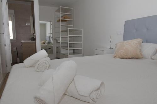 Un dormitorio con una cama blanca con toallas. en Moderno,tranquilo, entrada autónoma y fácil aparcamiento., en Madrid