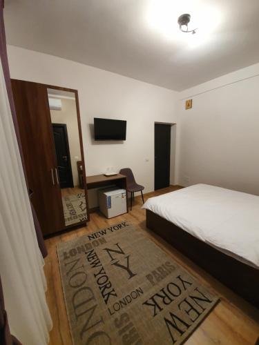 a bedroom with a bed and a television and a rug at Vily Luxury Rooms in Focşani