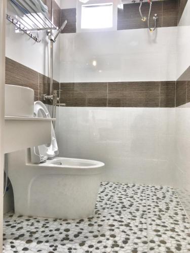 bagno con servizi igienici bianchi e pavimento in bianco e nero. di Hoang Vu Guest House a Da Lat