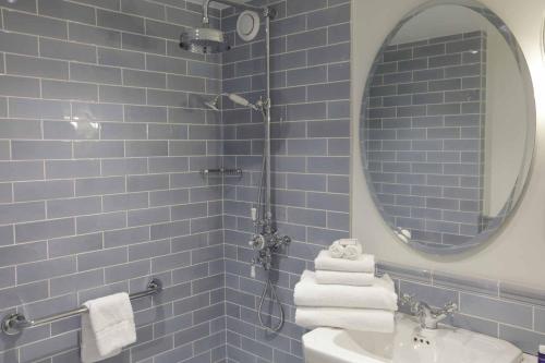 a blue tiled bathroom with a sink and a mirror at Cahernane House Hotel in Killarney