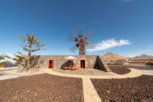 a windmill in the desert with a person sitting in front at La Molina NK in Tindaya
