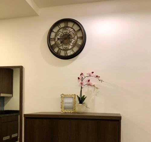 a clock on a white wall with a vase with flowers at Sky D'Mont Suites in Genting Highlands
