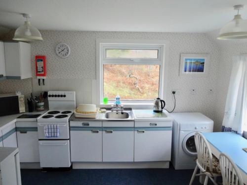 a kitchen with a sink and a stove and a window at Tigh-na-Mara in Lochinver