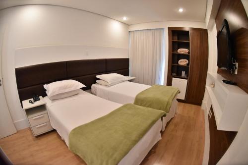 a hotel room with two beds and a television at Cordilheira Hotel in Serra Negra