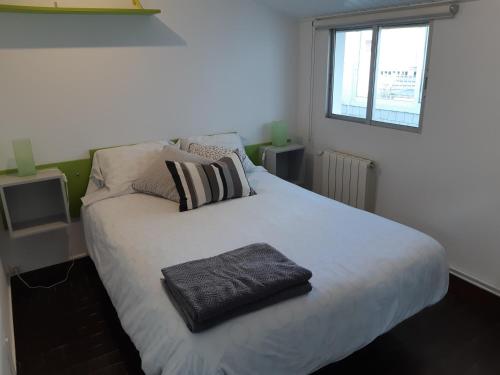 Un dormitorio con una cama blanca con una toalla negra. en Apartamento en vivienda unifamiliar, con plaza de garaje, en Santiago de Compostela