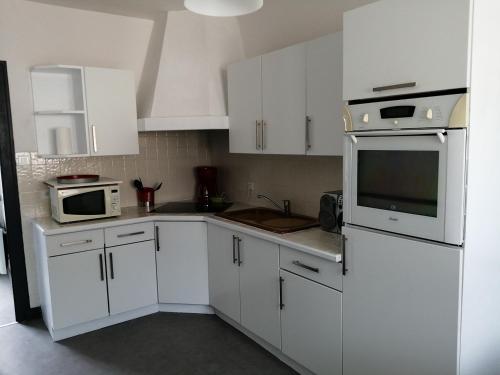 une cuisine avec des armoires blanches et des appareils électroménagers blancs dans l'établissement Maison de vacances au cœur des Sables d’Olonne, à Les Sables-dʼOlonne