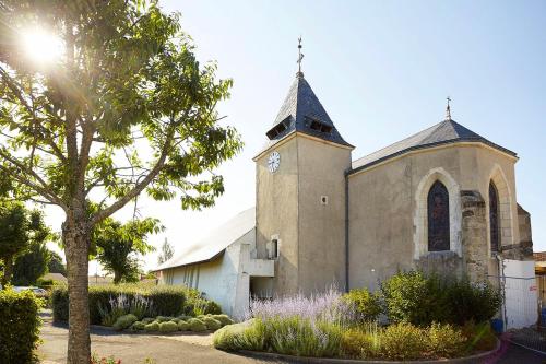 une ancienne église avec une tour d'horloge dans un jardin dans l'établissement Un petit coin de campagne dans le pays de Saint-Gilles, à Saint-Maixent-sur-Vie