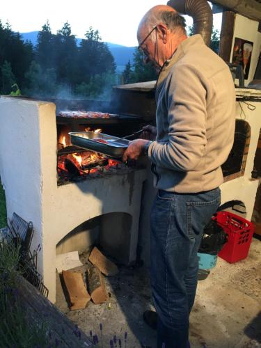 un homme plus âgé debout à côté d'un four extérieur dans l'établissement chambres d'hôtes des Bauges ROUTE 26 57, à La Motte-en-Beauges