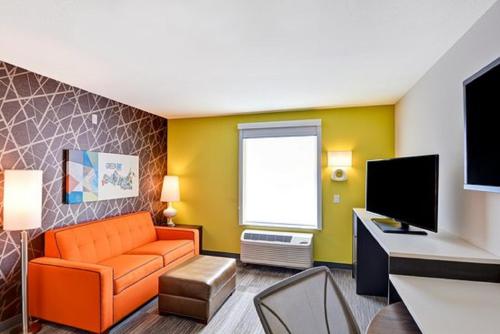 a living room with an orange couch and a television at Home2 Suites By Hilton Columbus/West, OH in Columbus
