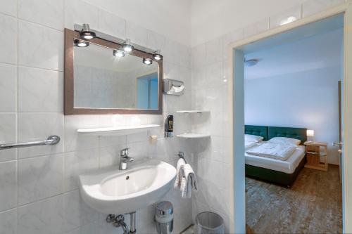 een badkamer met een wastafel, een spiegel en een bed bij Hotel Krone in Bingen am Rhein