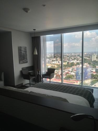 a bedroom with a large window with a bed and a desk at Baruk Guadalajara Hotel de Autor in Guadalajara