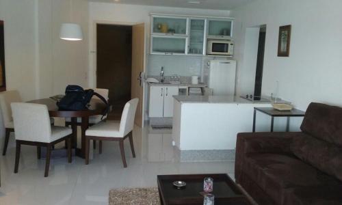 Una sala de estar con una mesa y una cocina. en Angra dos Reis Apartamento com Vista para o Mar 6 Condomínio Porto Bali Complexo Mercure, en Angra dos Reis