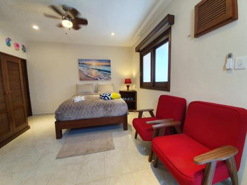 a bedroom with a bed and a red chair at Coralito Malecon Luxury Studio in Isla Mujeres