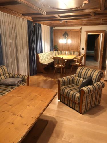a living room with two couches and a wooden table at Alpenhotel Widderstein in Mittelberg