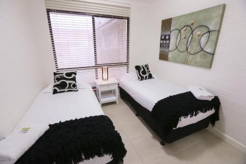 two twin beds in a room with a window at Mildura Holiday Villas in Mildura