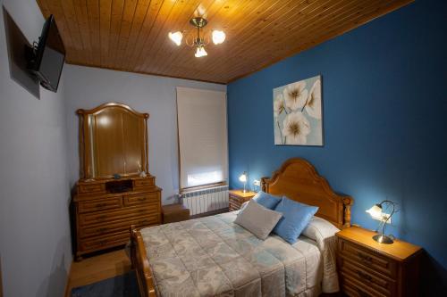 a bedroom with blue walls and a bed with a dresser at Casa Chuss in Sober