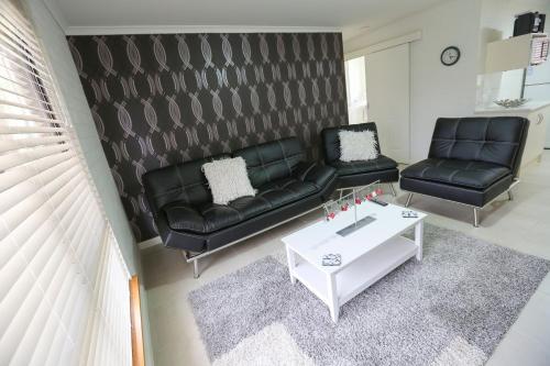 a living room with two black leather couches and a table at Mildura Holiday Villas in Mildura