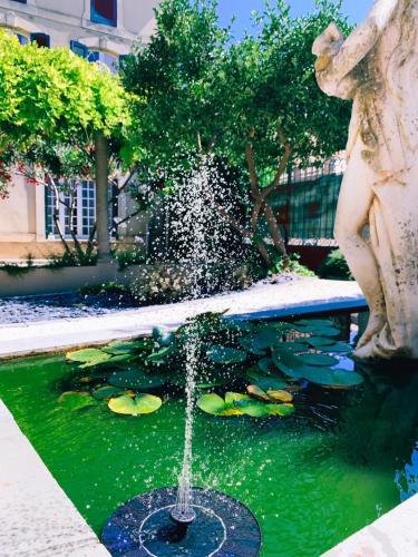 a water fountain with a statue next to a pond with lilies at Maison de maître à BRAM # Jacuzzi in Bram