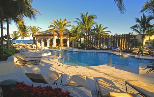 einen großen Pool mit Stühlen und Palmen in der Unterkunft Kimpton Vero Beach Hotel & Spa, an IHG Hotel in Vero Beach