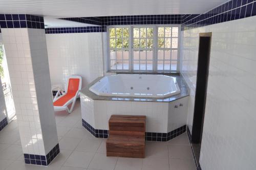 baño con bañera, silla y ventana en Hotel da Montanha, en Miguel Pereira