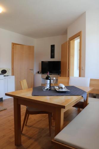 uma mesa de madeira com um prato e um copo de vinho em Haus Gastl em Arzl im Pitztal