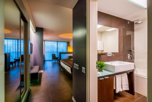 a bathroom with a sink and a bed in a room at RR Hotel da Rocha in Portimão