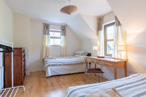 a bedroom with two beds and a desk and a window at Álaind Lodges, Sneem in Sneem