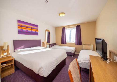 a hotel room with two beds and a tv at Stables Inn, Aintree in Liverpool