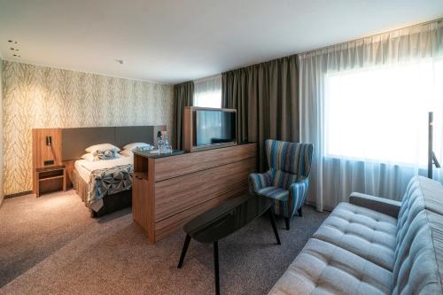 een hotelkamer met een bed, een tv en een bank bij HP Park Plaza in Wrocław