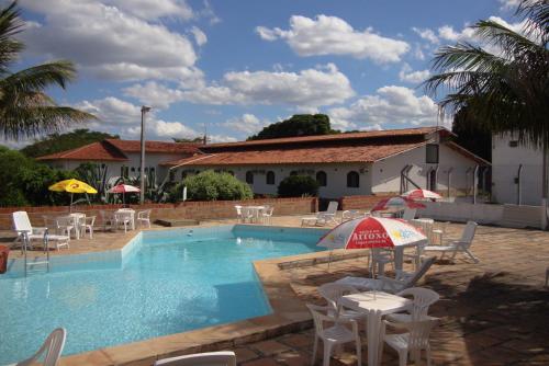 a swimming pool with chairs and tables and an umbrella at Pousada Ecológica das Bromélias in Morro do Chapéu