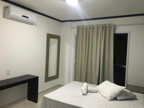 a white room with a bed with a window and aburning at Apartamentos Primavera Guarujá in Guarujá