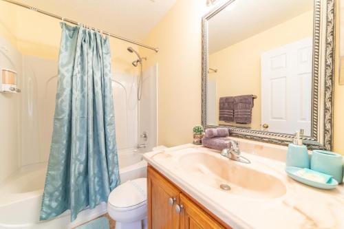 La salle de bains est pourvue d'un lavabo, de toilettes et d'un miroir. dans l'établissement Lovely Disney Vacation House, à Orlando