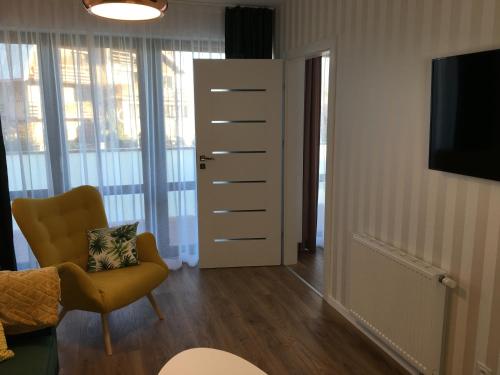 a living room with a yellow chair and a television at Apartament Gold Triventi in Karpacz