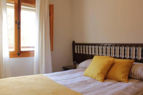 Un dormitorio con una cama con almohadas amarillas y una ventana en Apto. Rural Las Candelas. La Covatilla en Candelario