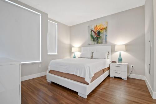 a white bedroom with a white bed and a painting on the wall at Global Luxury Suites at Downtown Mountain View in Mountain View