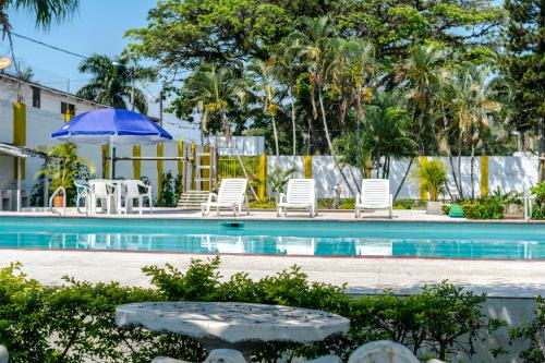 a swimming pool with chairs and a blue umbrella at Hotel Villa Bosco in Palmira