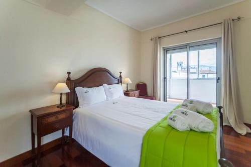 een slaapkamer met een groot wit bed en een raam bij Deluxe Marina Apartment - Azorean Butler in Ponta Delgada