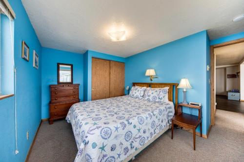 ein blaues Schlafzimmer mit einem Bett und einer Holzkommode in der Unterkunft The Best Little Beach House on the Oregon Coast! in Lincoln Beach