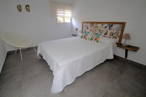a bedroom with a white bed and a chair at Finca Arbequina in Pájara