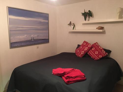 Un dormitorio con una cama con almohadas rojas y una pintura en Beautiful location Copenhagen/Malmö en Malmö