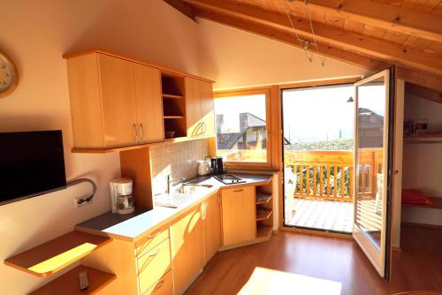a kitchen with wooden cabinets and a large window at Unterbi Apartments in Appiano sulla Strada del Vino