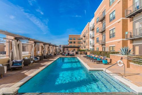 a swimming pool with chairs and a building at Regal Stays Corporate Apartments - McKinney Ave - Uptown Dallas in Dallas