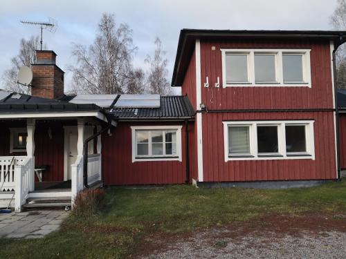a red house with white windows and a porch at Romme stugby in Borlänge