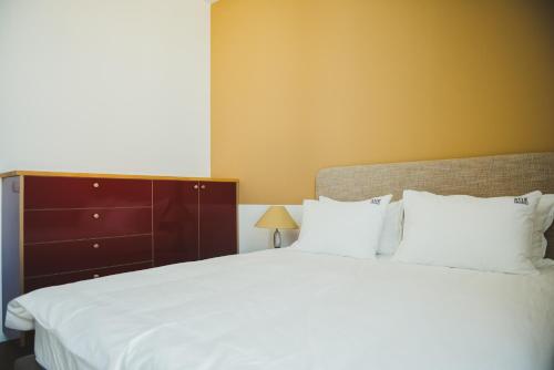 a bedroom with a large white bed and a dresser at The Rambam Residence - By Localz Group in Tel Aviv