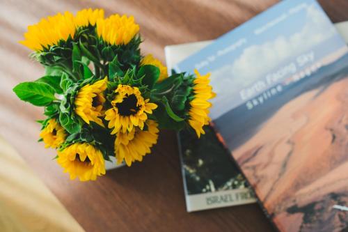 a bouquet of sunflowers sitting next to a book at The Rambam Residence - By Localz Group in Tel Aviv