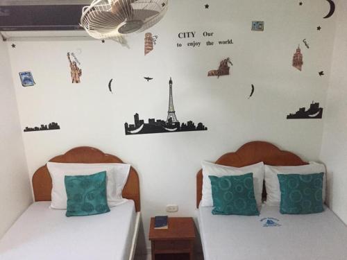 a bedroom with two twin beds with cities on the wall at Hotel Monaco De Riohacha in Ríohacha