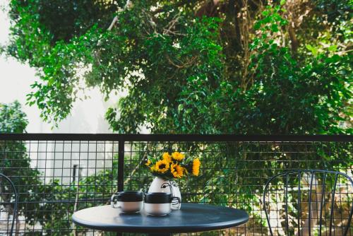 a table with two cups and a vase with flowers on it at The Rambam Residence - By Localz Group in Tel Aviv